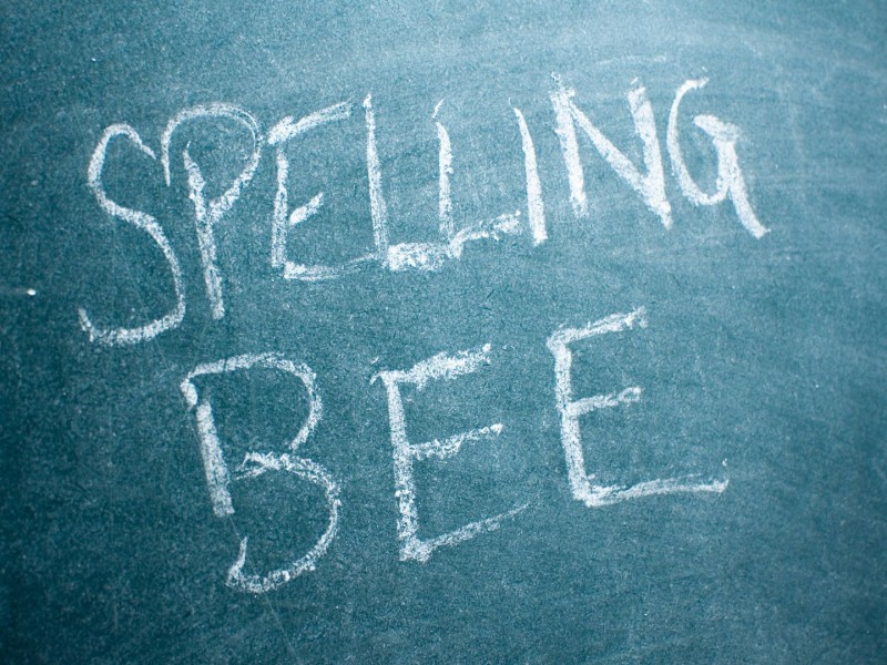 "Spelling Bee" written in white on a green chalkboard.