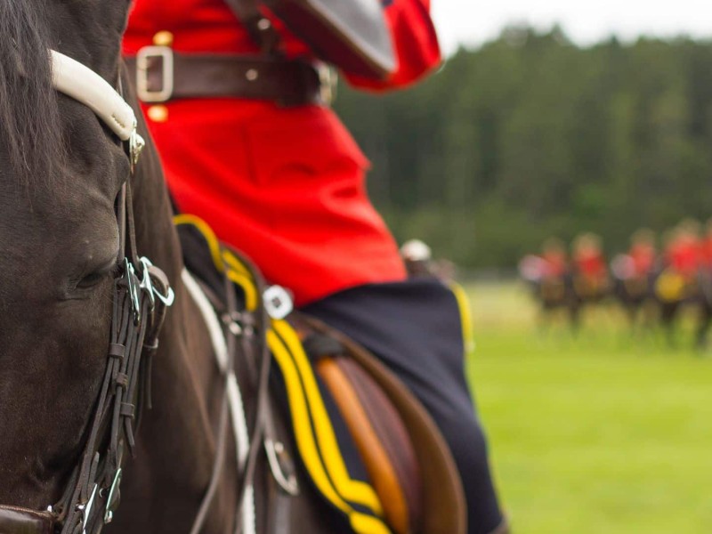 An RCMP in mountie uniform on a horse.
