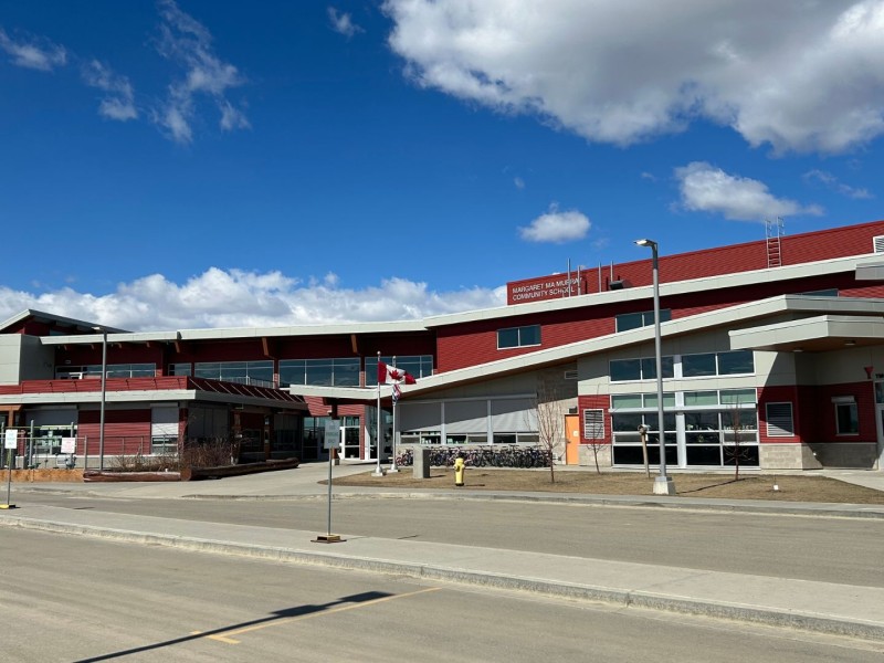 A picture of a red and white school with a Canadian flag in the front.