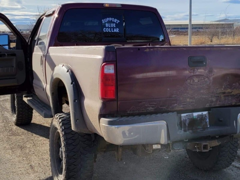A burgundy truck with the door open and a sticker that says "Support Blue Collar" on the back window.