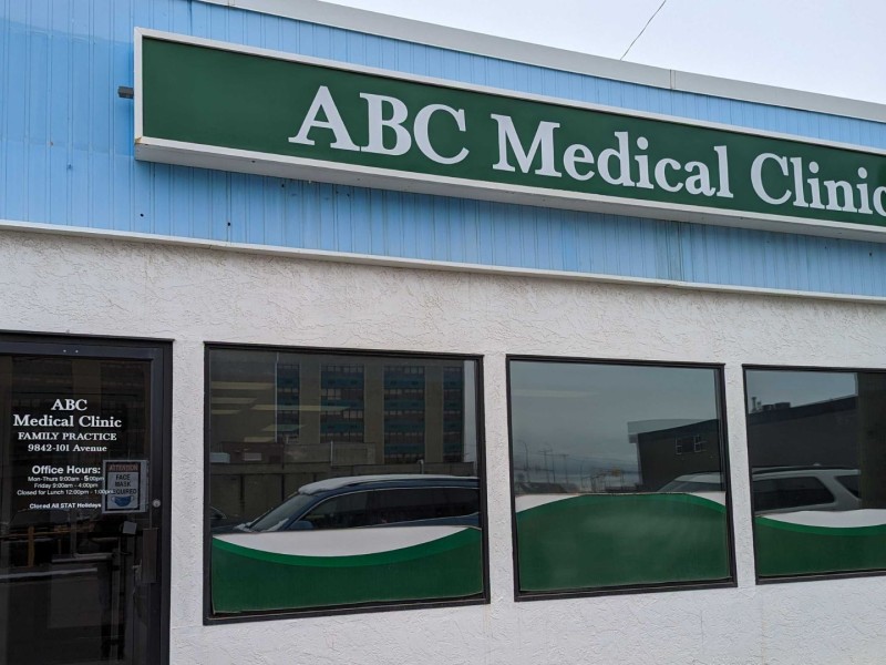 A white building with blue on top and a sign that says ABC Medical Clinic.
