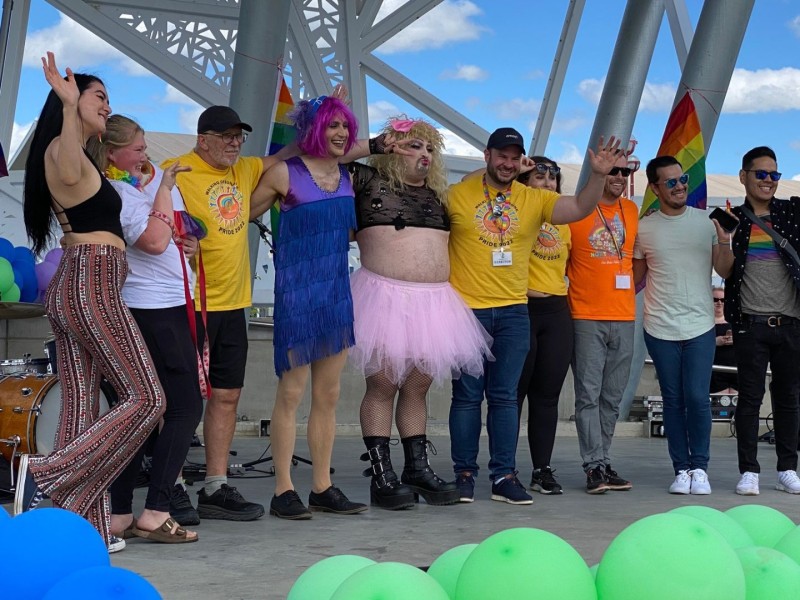 A group of people, some in drag, standing on the Centennial Park stage.