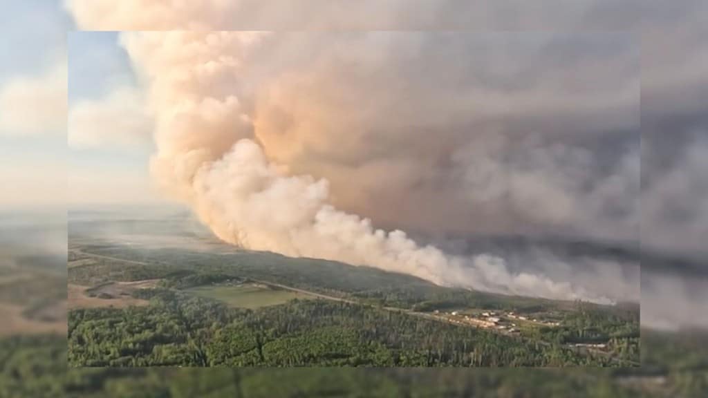 A large cloud of smoke taken from the air over a forested area.