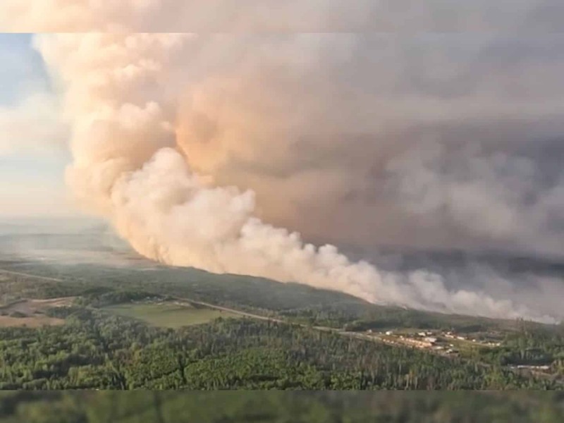 A large cloud of smoke taken from the air over a forested area.