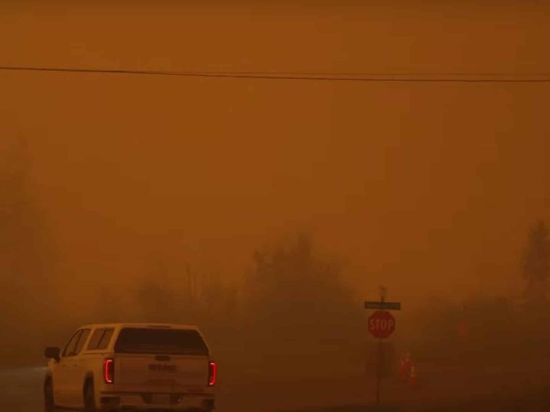A red, hazy picture of a white truck at a stop sign before a highway.