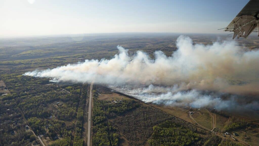 An aerial view of a wildfire and lots of white smoke from a green area, north of Charlie Lake.