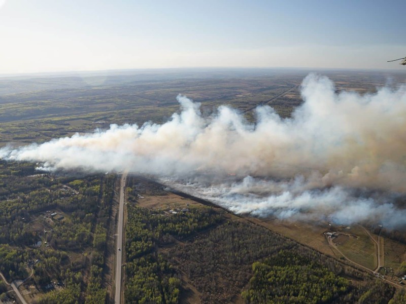 An aerial view of a wildfire and lots of white smoke from a green area, north of Charlie Lake.