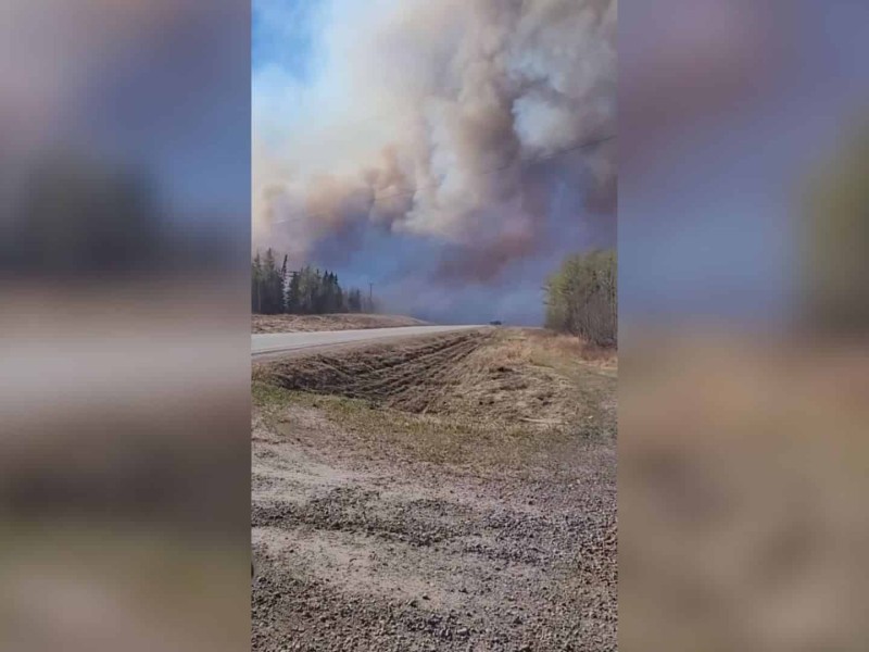 A picture of a highway with trees next to it on fire.