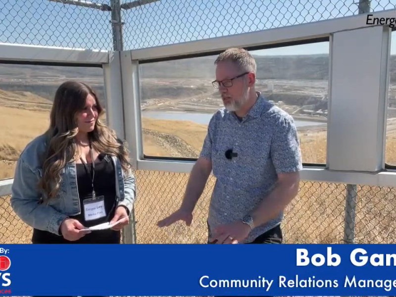 Two people talking in front of a chain link fence