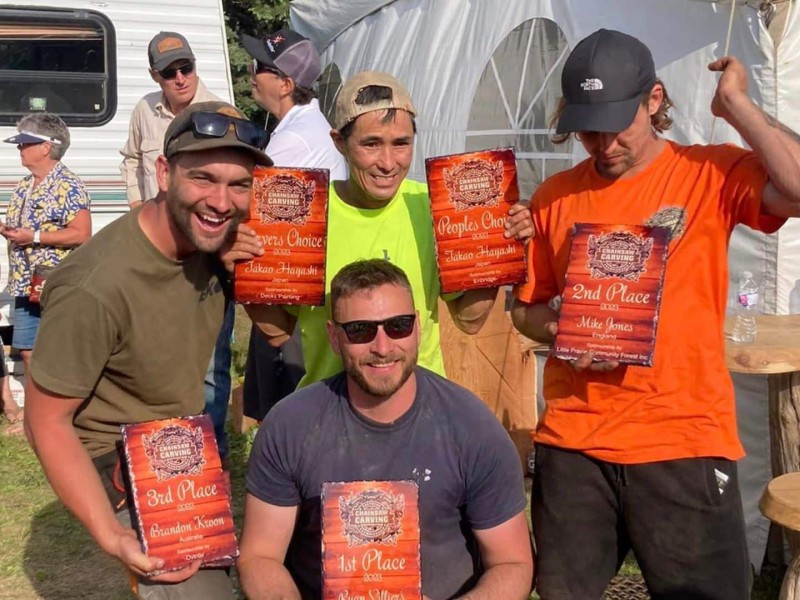 Four men holding awards for the chainsaw charving championship in Chetwynd.