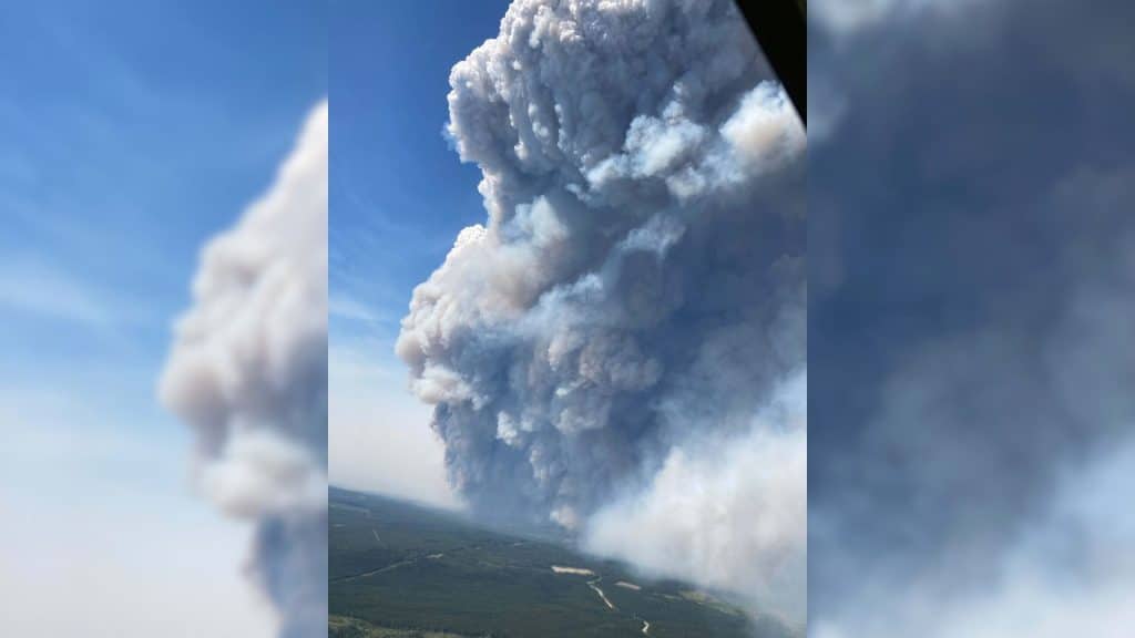 An aerial shot of a plume of smoke going up into blue skies.