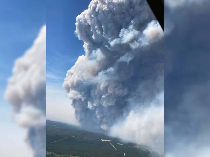 An aerial shot of a plume of smoke going up into blue skies.
