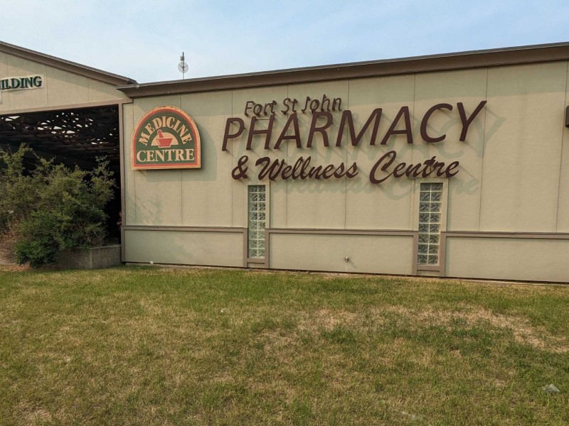 A grey building with a sign that reads Medicine Centre and Fort St. John Pharmacy & Wellness Centre on the front.
