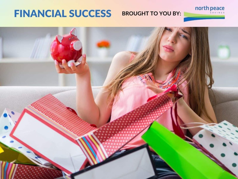 A person covered in shopping bags looking concerned at their piggy bank