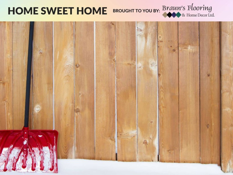 A snow shovel leaning against a fence