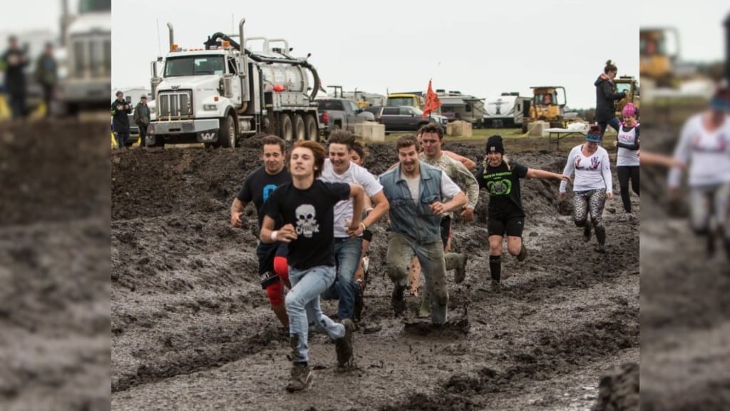 A group of people running through a muddy field.