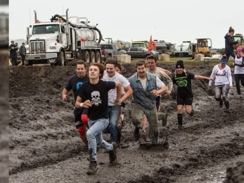 A group of people running through a muddy field.