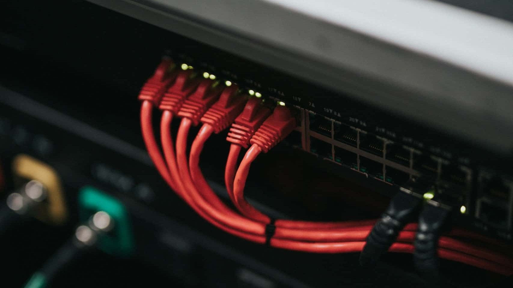 A server rack with several red ethernet cables plugged into it.