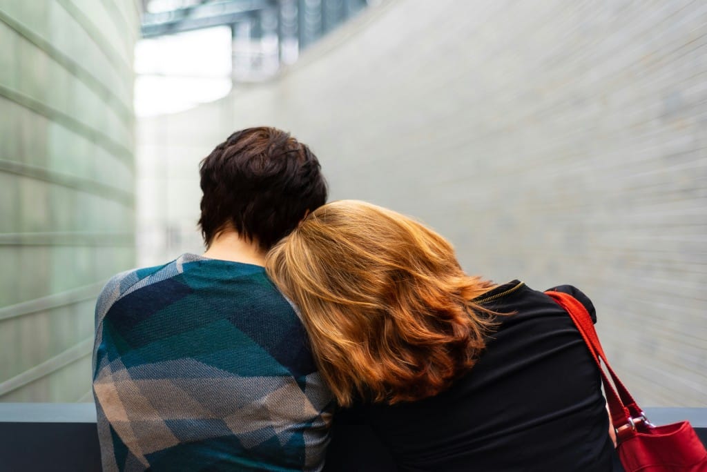 Two women leaning together. The annual Day of Mourning takes place on April 28th.