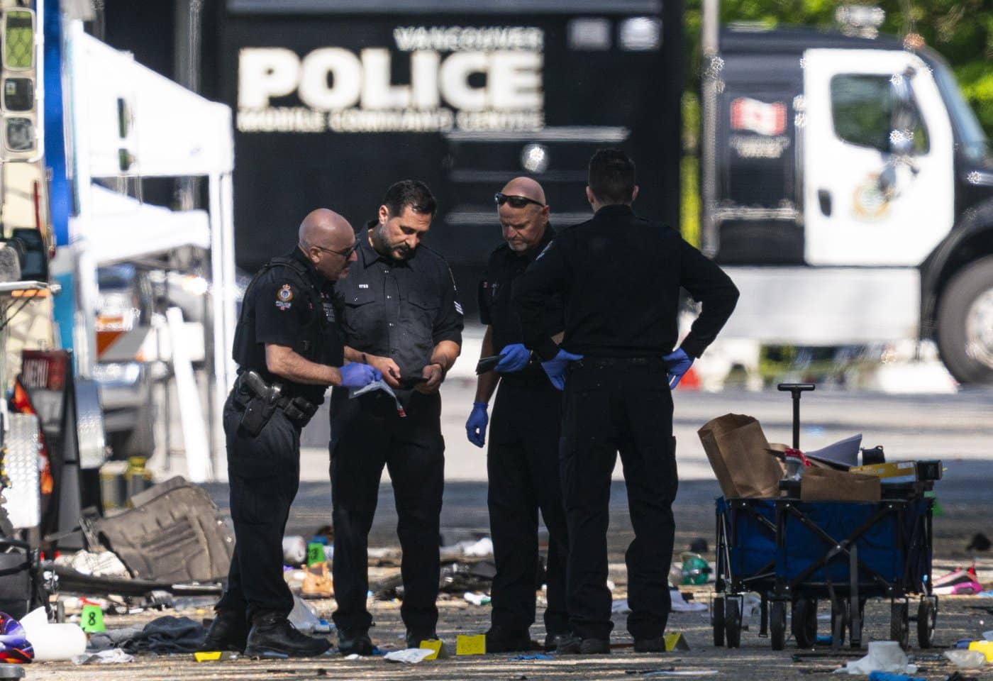 Members of the Vancouver Police forensics team examine a victim's phone while investigating the scene where a vehicle drove into crowd at a street festival Saturday evening in Vancouver, Sunday, April 27, 2025.