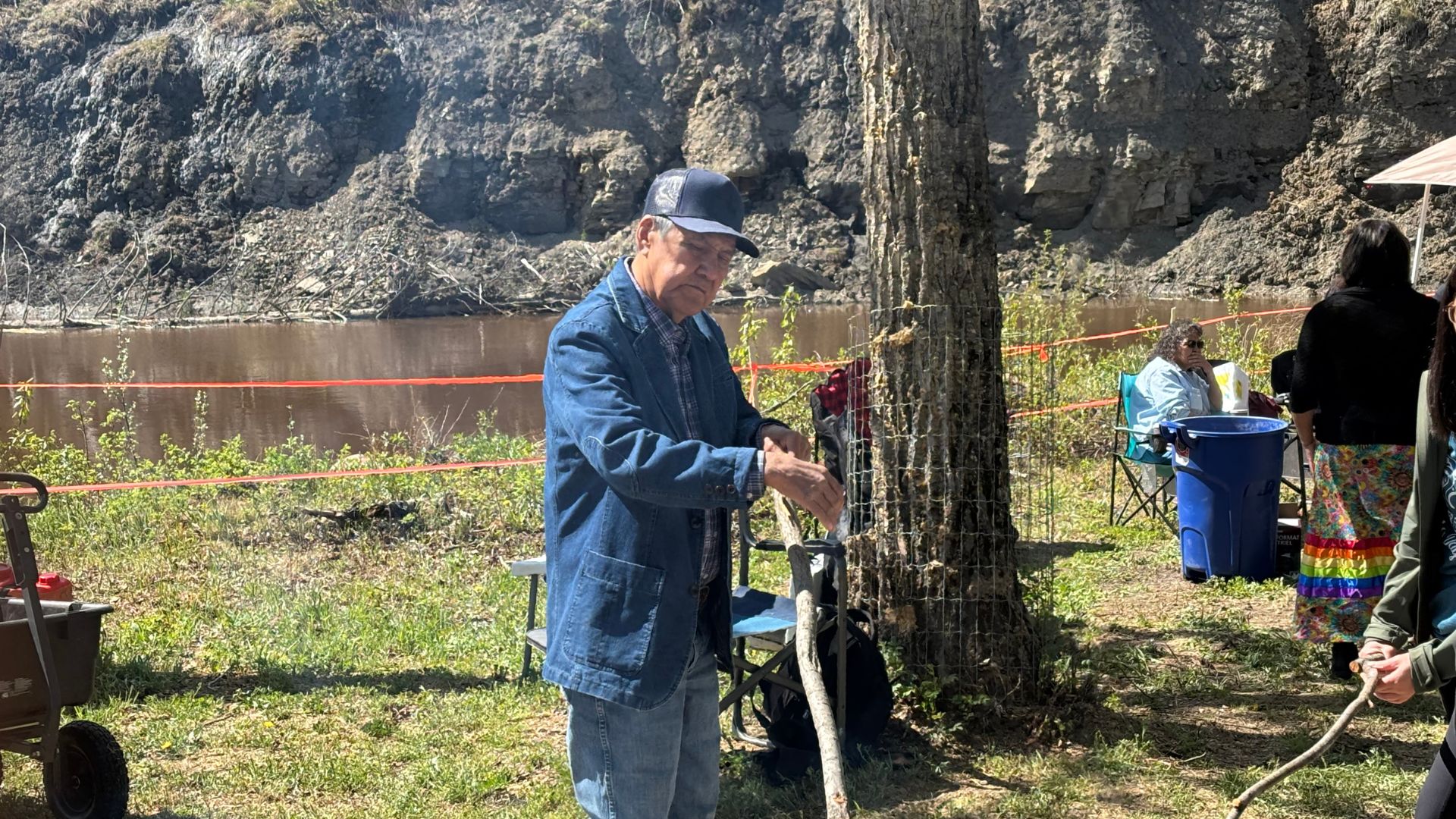 Doig River First Nation Elder Gerry Attachie warms up some bannock by the fire during Doig Day 2025 on May 22nd.