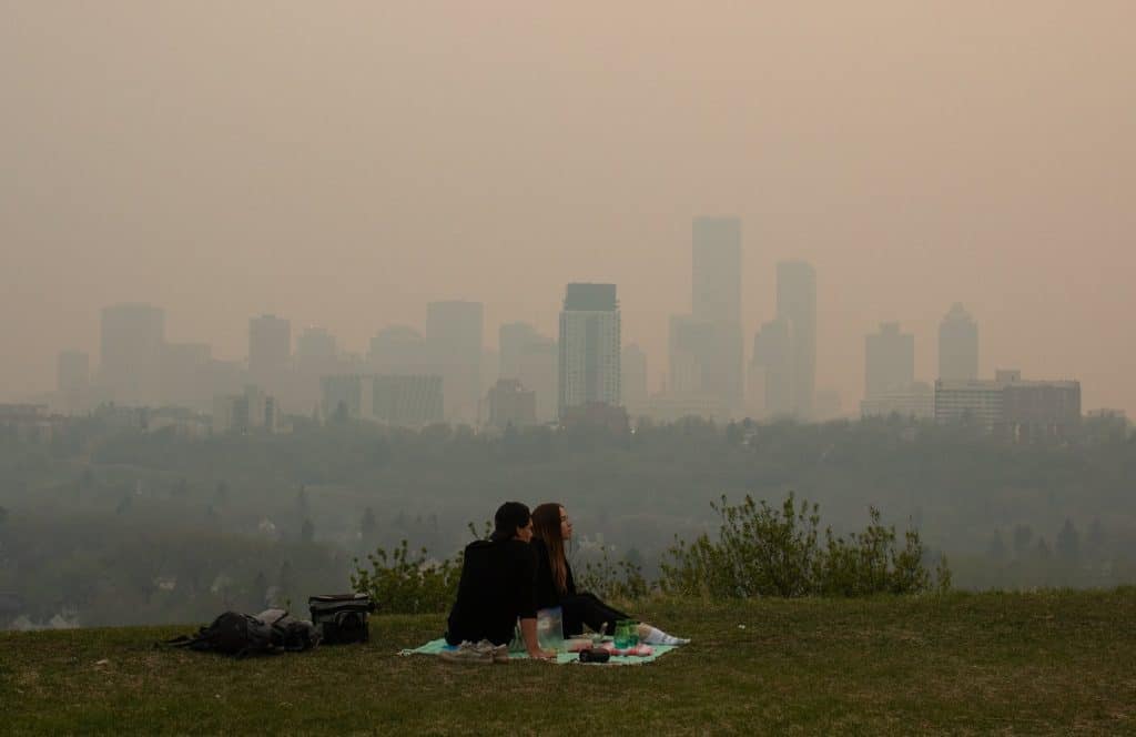 Smoke from wildfires blankets the city as a couple has a picnic in Edmonton on May 11th, 2024. (THE CANADIAN PRESS/Jason Franson)