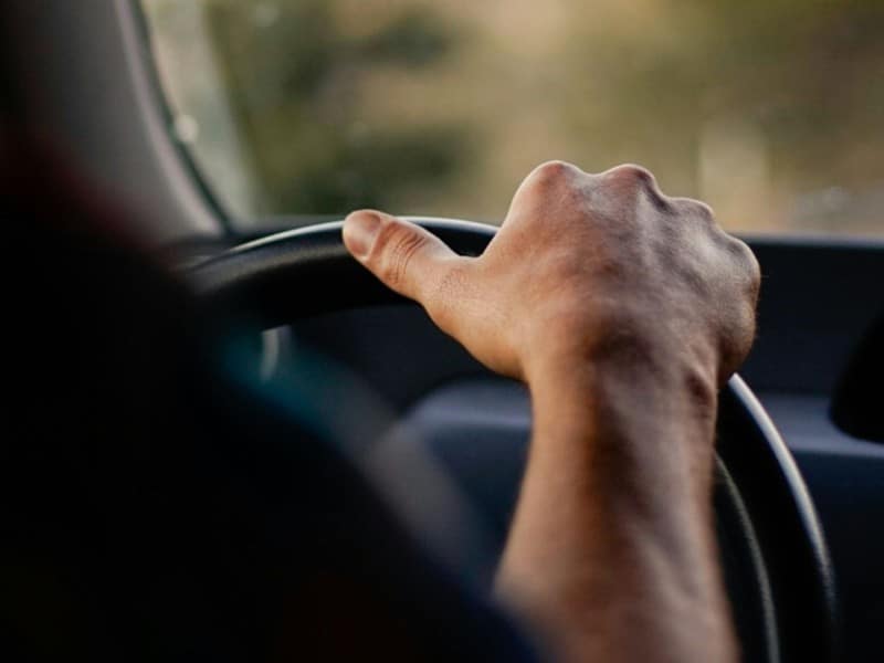 Driver behind steering wheel. (Ryan Porter/Unsplash)