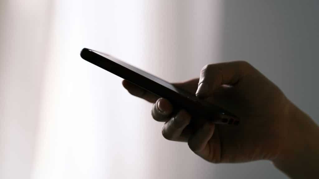 Hand holding cell phone. (DuoNguyen/Unsplash)