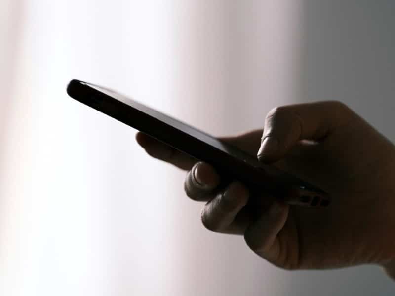 Hand holding cell phone. (DuoNguyen/Unsplash)