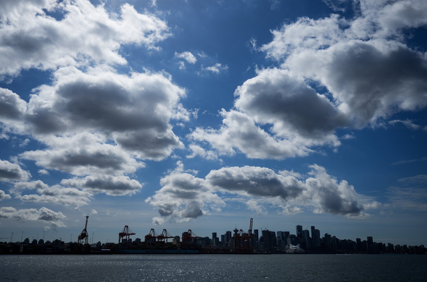 The downtown skyline and cranes at port are silhouetted while seen from the harbour, in Vancouver, on Tuesday, April 25, 2023. THE CANADIAN PRESS/Darryl Dyck