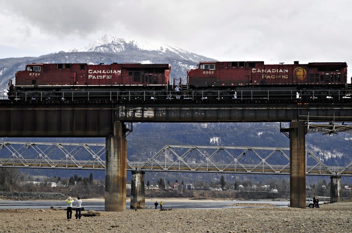 REVELSTOKE, BC — 14/03/10 — People stroll along the banks of the Columbia River in Revelstoke as a train passes by overhead on Sunday, March 14. Photo by Daniel Hayduk