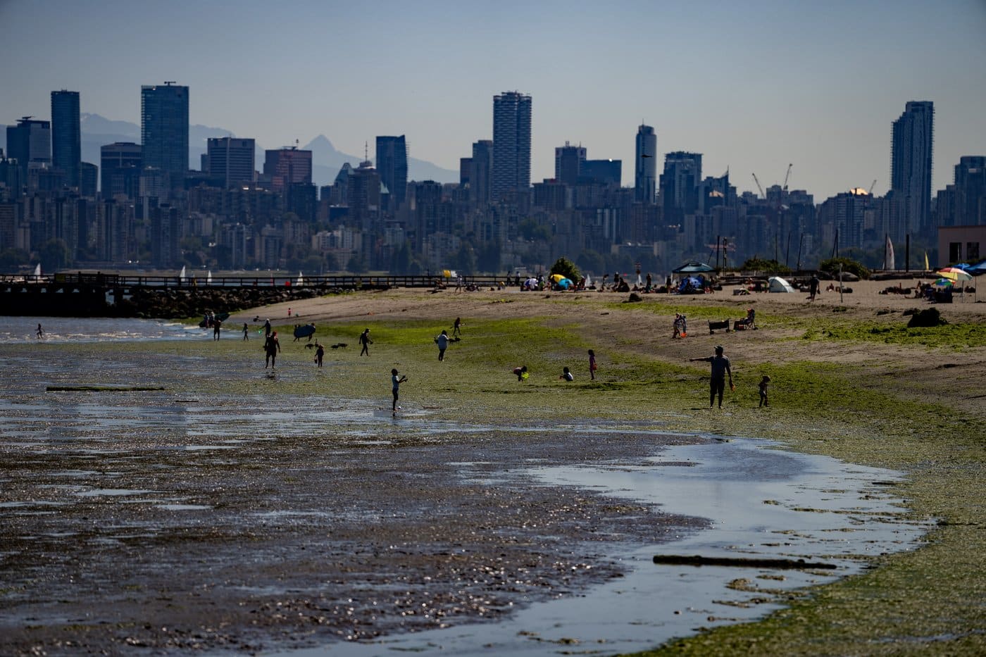 People walk on the beach during low tide in Vancouver, B.C., Sunday, July 7, 2024. THE CANADIAN PRESS/Ethan Cairns