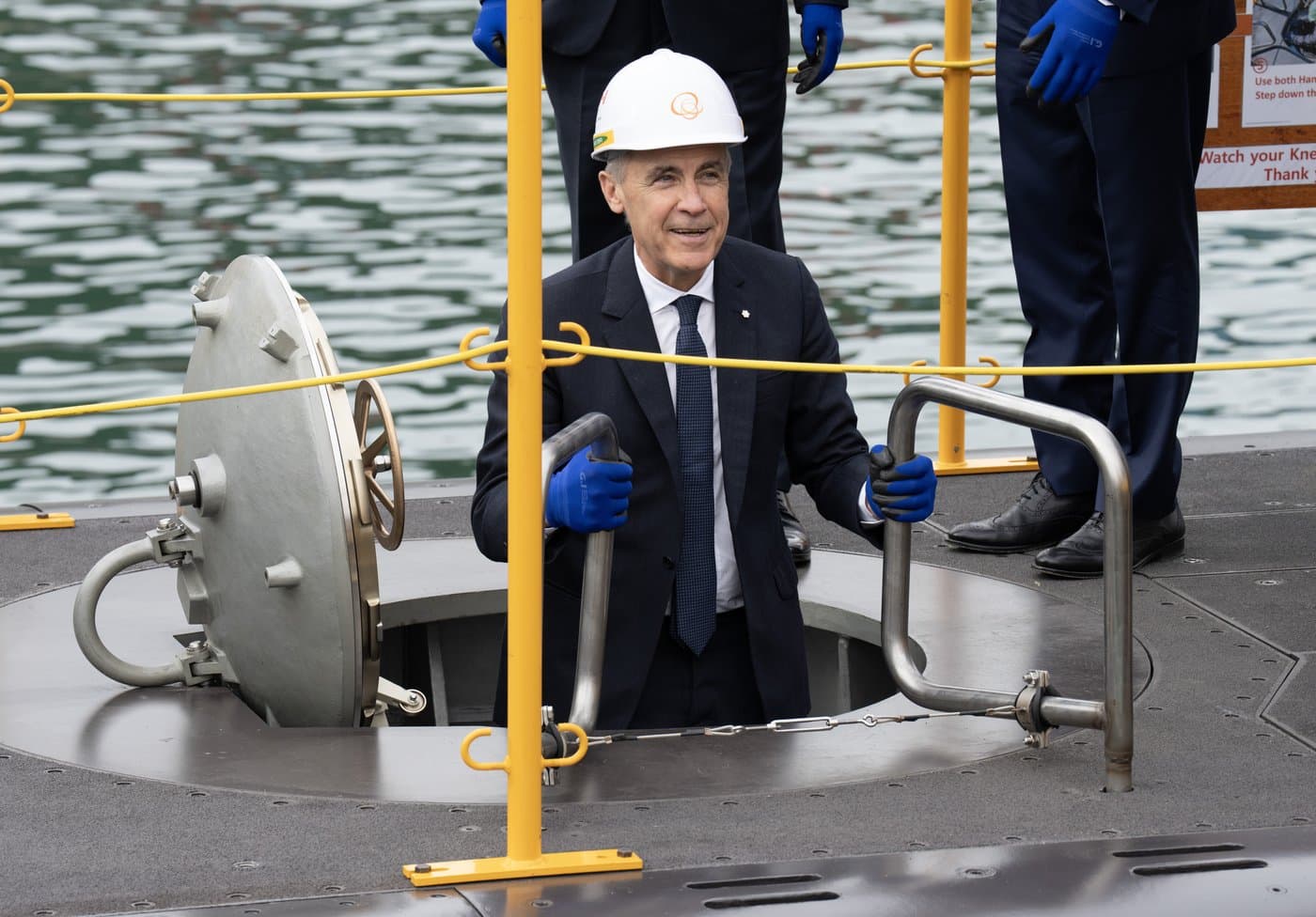 Prime Minister Mark Carney smiles as he climbs down a ladder into a submarine during a tour of the Hanwha Ocean Shipyard in Geoje Island, South Korea, on Thursday, Oct. 30, 2025. THE CANADIAN PRESS/Adrian Wyld