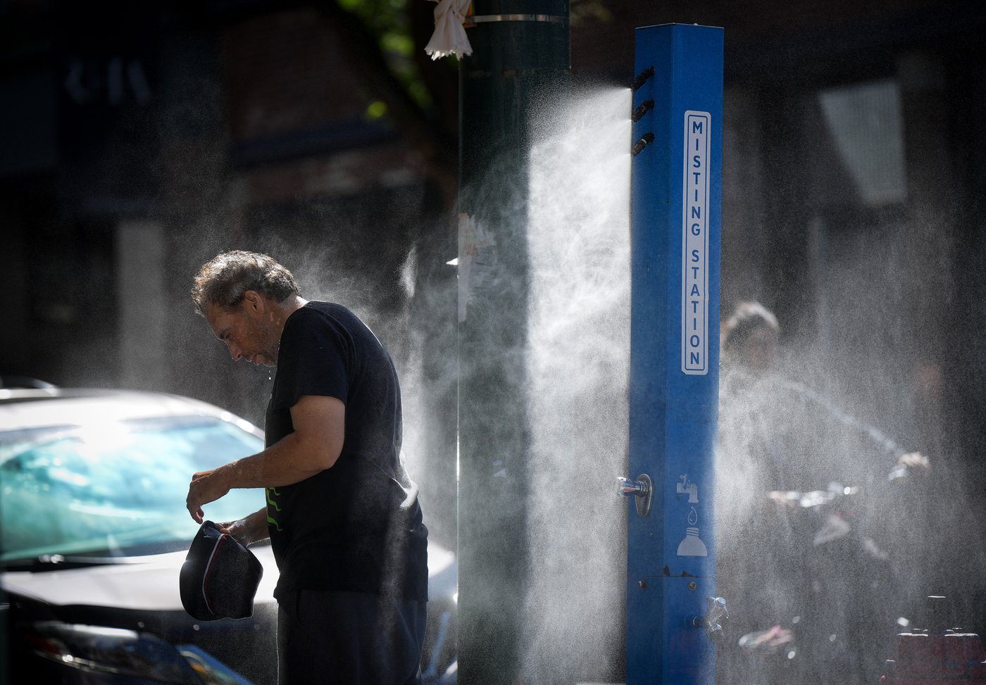 A man cools off at a temporary misting station deployed by the city in the Downtown Eastside due to a heat wave in Vancouver on Wednesday, Aug. 16, 2023. THE CANADIAN PRESS/Darryl Dyck
