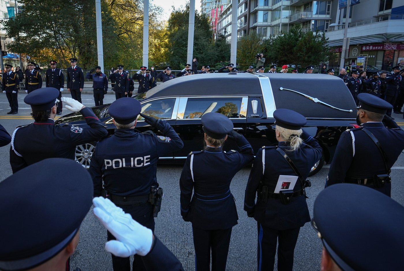Police officers and firefighters salute as a hearse carries RCMP Const. Shaelyn Yang's casket after her regimental funeral, in Richmond, B.C., on Wednesday, November 2, 2022. The 31-year-old officer was stabbed to death while helping a City of Burnaby employee issue an eviction notice to a man living in a tent at a local park. THE CANADIAN PRESS/Darryl Dyck