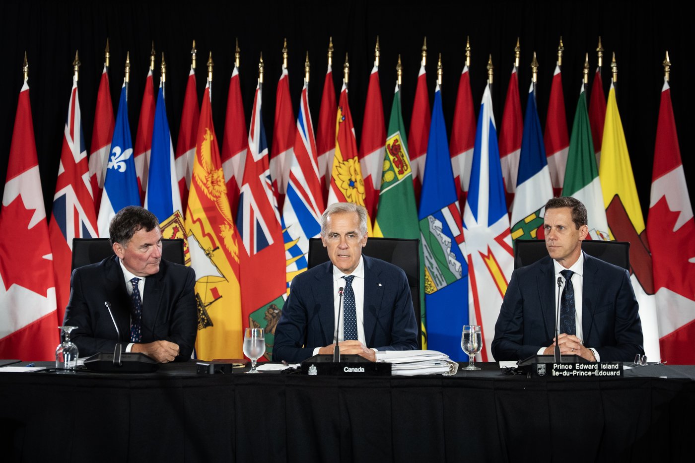 Prime Minister Mark Carney, centre, addresses Canada's premiers with Canada-U.S. Trade Minister Dominic LeBlanc, left, and Prince Edward Island Premier Rob Lantz during first ministers meetings in Charlottetown on Thursday, July 23, 2026. THE CANADIAN PRESS/Darren Calabrese