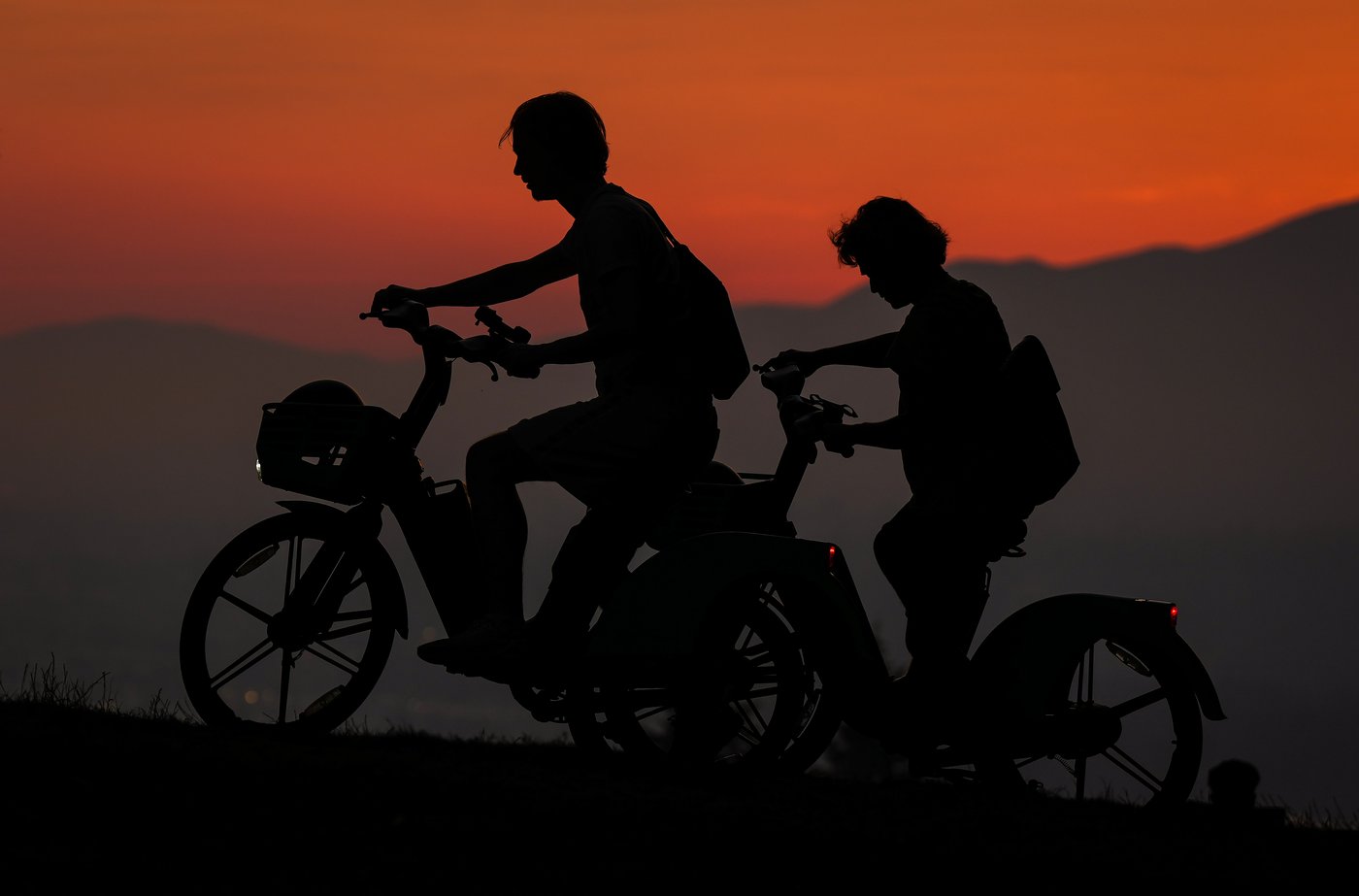 People on bikes are silhouetted at sunset at Burnaby Mountain Park as smoke from wildfires burning in Canada and the U.S. begins to settle over the region, in Burnaby, B.C., on Tuesday, July 21, 2026. THE CANADIAN PRESS/Darryl Dyck